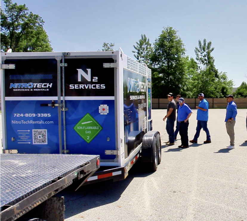 NitroTech nitrogen trailer rear view with field crew gathered at industrial facility — real deployment photo